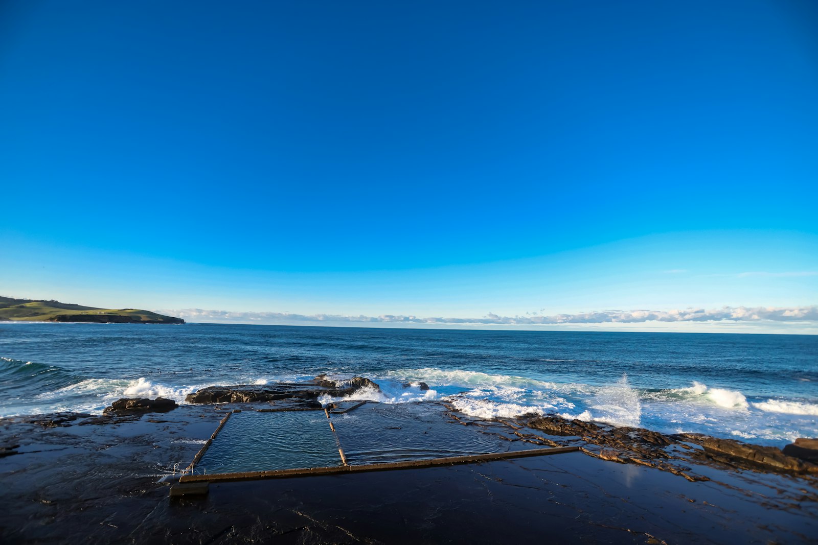 Ocean waves crash on rocky shore with a natural pool